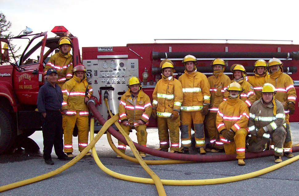 slide1 Firefighters in gear posing in front of a fire engine with hoses